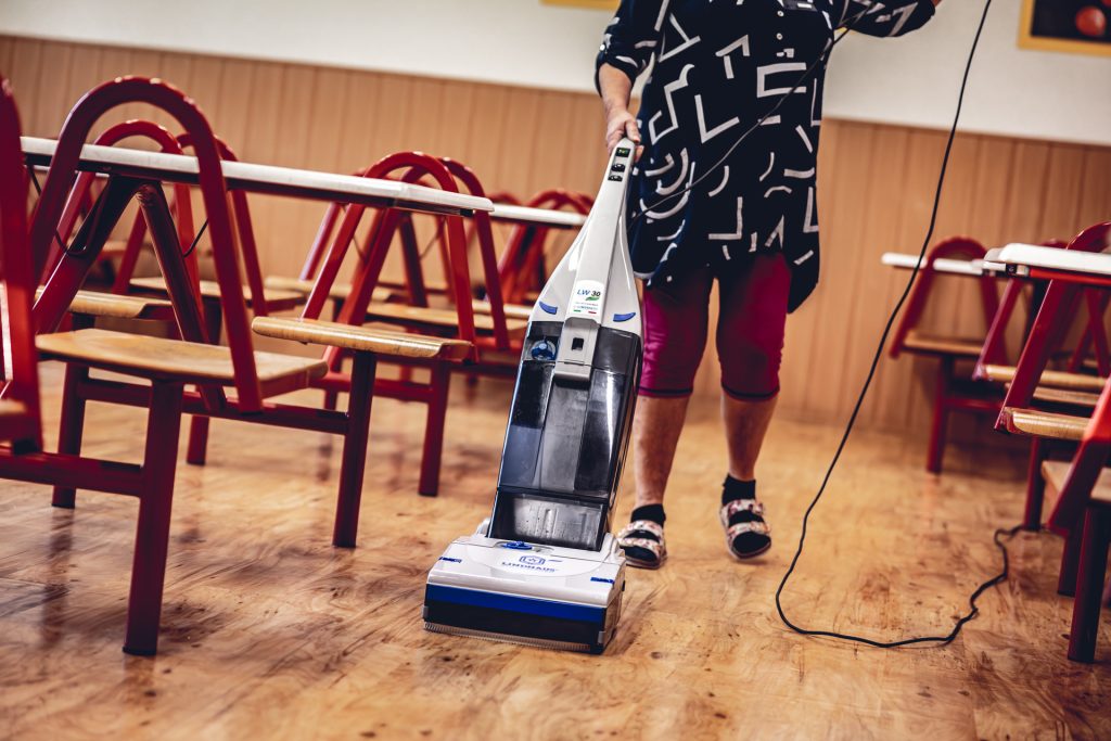 Žena čistí podlahu jedálne školy pomocou podlahového umývacieho stroja LINDHAUS LW30